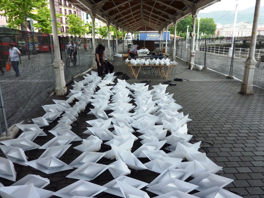 VOYAGE by Aether & Hemera, assembling our flotilla of colourful origami lit paper boats floating on the water. From London to Bilbao