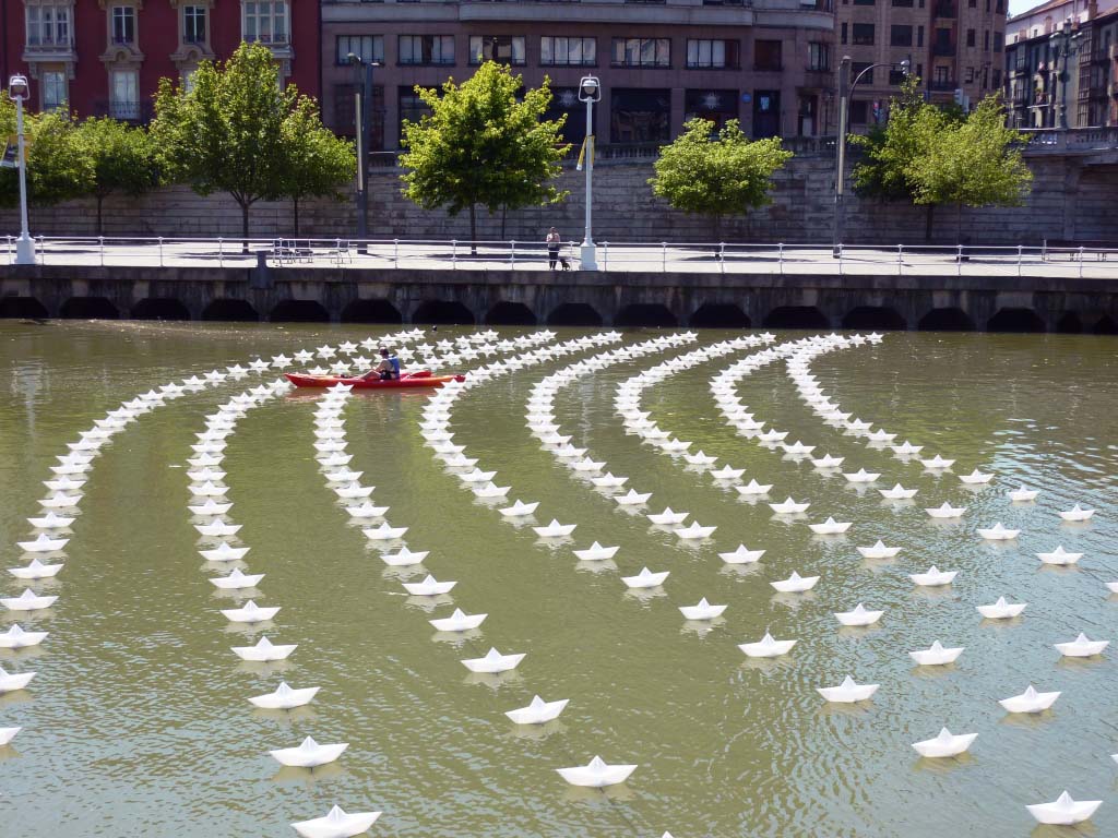 VOYAGE by Aether & Hemera, a  flotilla of colourful origami lit paper boats floating on the water. From London to Bilbao