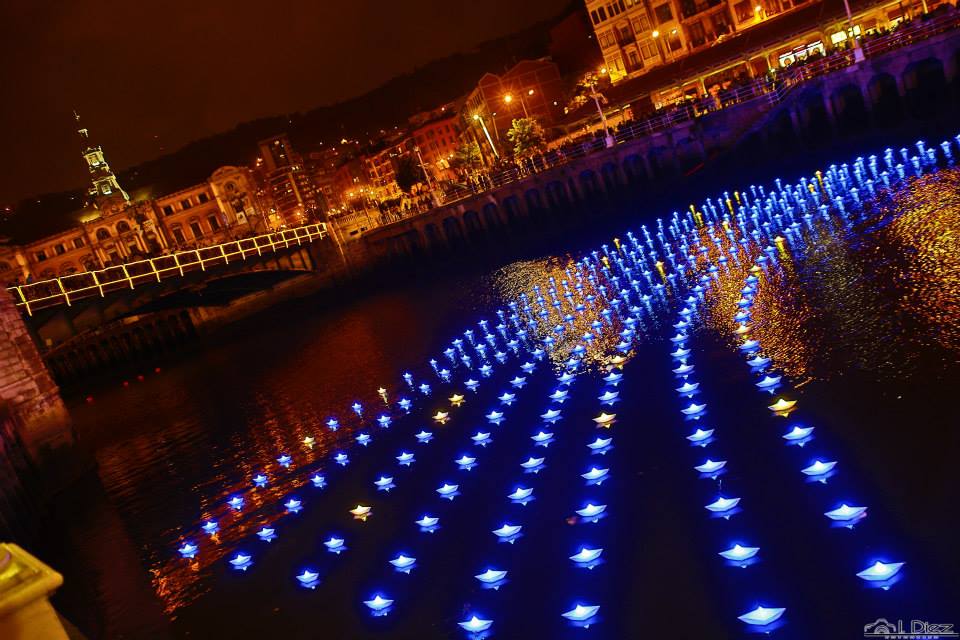 VOYAGE by Aether & Hemera, a  flotilla of colourful origami lit paper boats floating on the water. From London to Bilbao