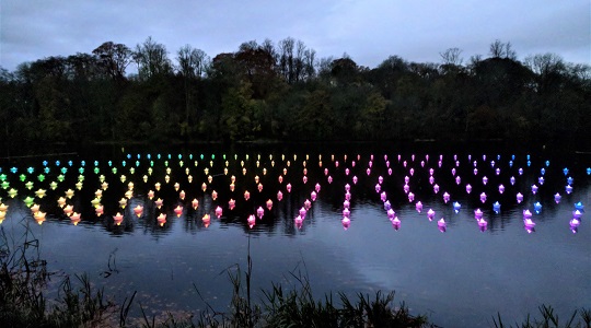 VOYAGE by Aether & Hemera, a  flotilla of colourful origami lit paper origami boats floating on the water. From London to Oxfordshire